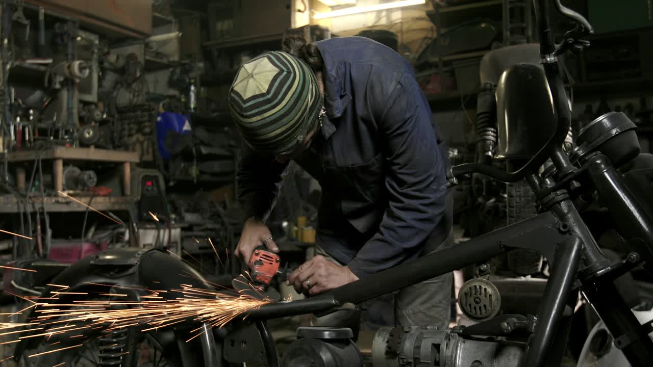 o homem está moendo aço de roda de motocicleta na garagem.