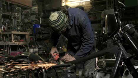 the man is grinding motorcycle wheel steel in the garage