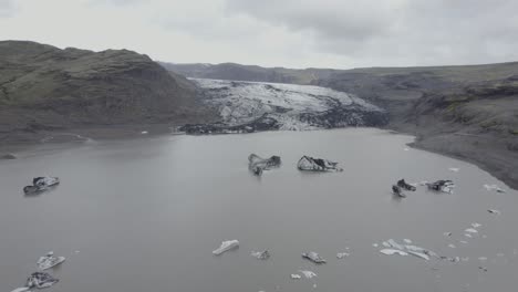 aerial drone view over a lagoon, towards the solheimajokull glacier, in cloudy iceland