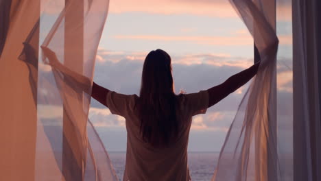 mujer feliz abriendo la cortina disfrutando del amanecer temprano en casa sintiendo una libertad pacífica relajándose en vacaciones mirando la hermosa vista del océano