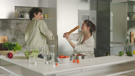 couple playfully 'fencing' with baguettes in a modern kitchen