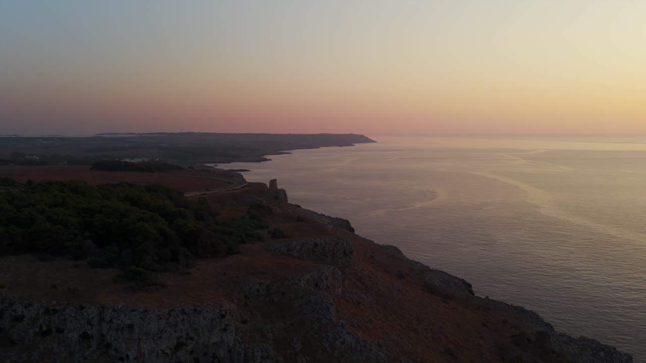 Aerial view of Torre Minervino watchtower and rugged coastline at sunrise. Colorful sky over calm sea. For travel or history content, Puglia, Italy