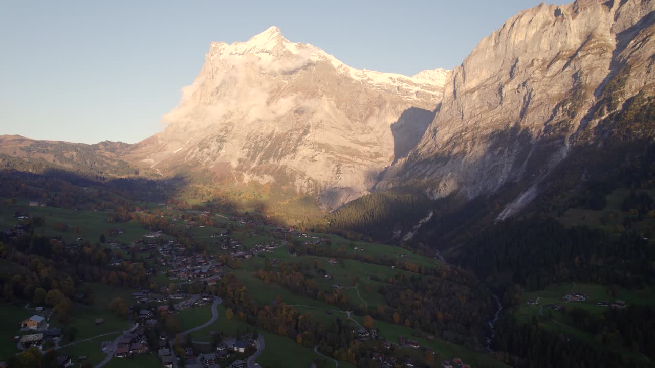 imágenes aéreas de drones dolly de derecha a izquierda sobre el pueblo de grindelwald con vistas al atardecer del monte wetterhorn y grosse scheidegg