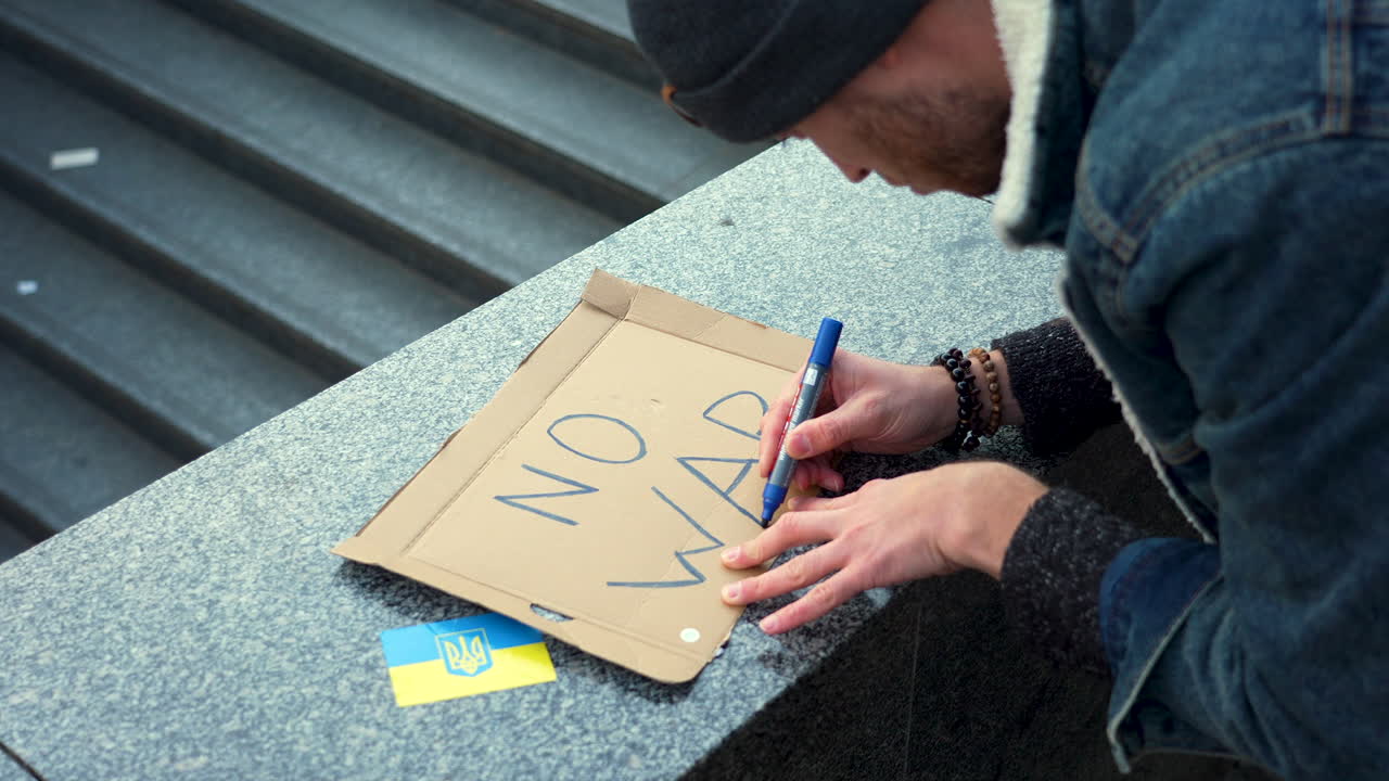 manifestante preparando un cartel contra la guerra en ucrania en una manifestación, praga