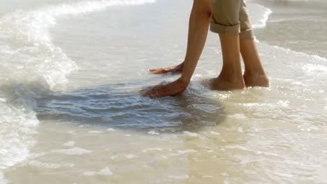 Unterer-Teil-Einer-Aktiven-älteren-Afroamerikanischen-Frau,-Die-Mit-Meereswellen-Am-Strand-Spielt-4k