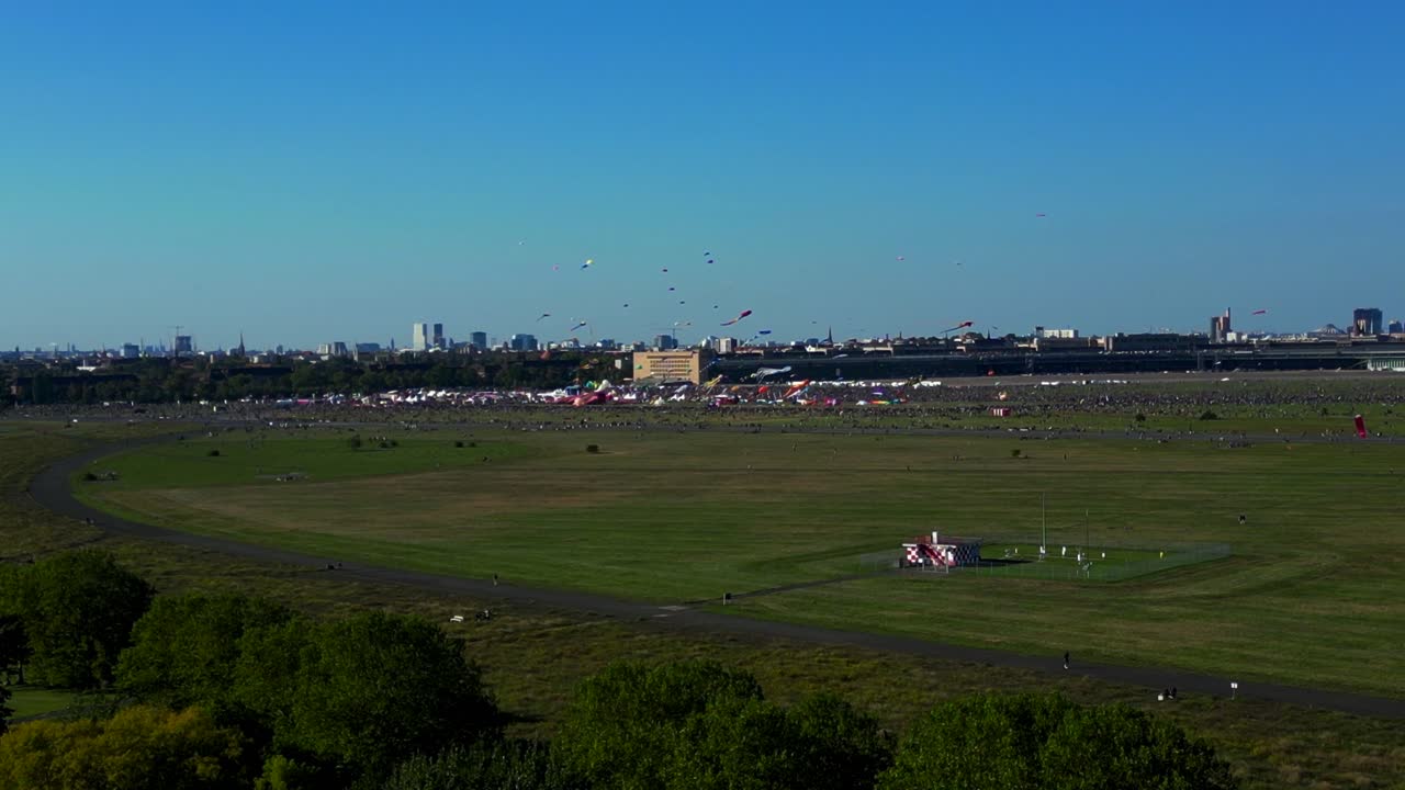 thousands of Berliners enjoying the giant kite festival on a sunny day at Tempelhofer Feld, the former Tempelhof Airport. Nice aerial view flight static tripod hovering drone