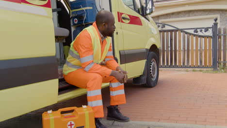 worried black medical assistance waiting on the ambulance at the entrance of a house