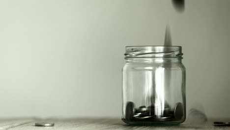 close up money coin falling into glass jar , a money saving , donation or business financial growth concept , 4k dci resolution , vintage retro color tone