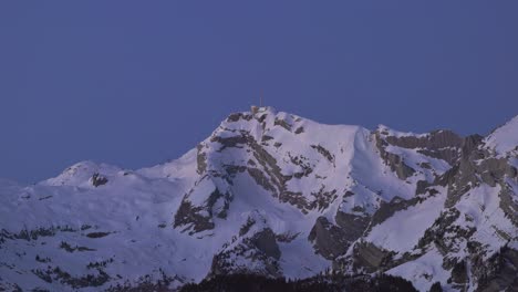 Witness-the-ethereal-charm-of-sunrise-over-a-snow-capped-mountain-range-silhouette-through-this-mesmerizing-drone-footage