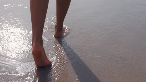 Cerrar-Los-Pies-De-Una-Mujer-Caminando-Descalzo-En-La-Playa-Disfrutando-De-La-Suave-Arena-Húmeda-Del-Mar-Turista-Femenina-En-Vacaciones-De-Verano