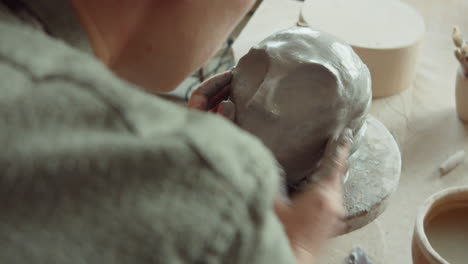 female artist sculpting head in clay