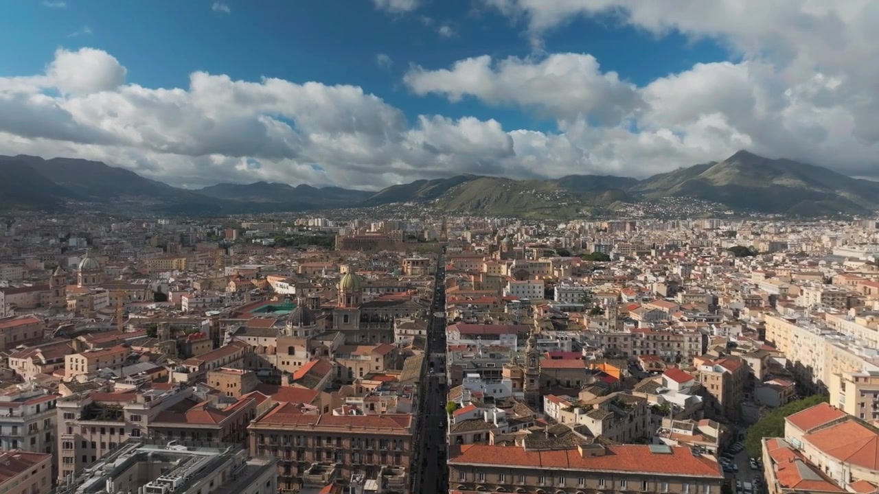 Vista aérea del centro de la ciudad de Palermo con tejados densos, una carretera central recta y montañas al fondo