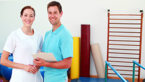 Smiling-physical-therapists-looking-at-clipboard