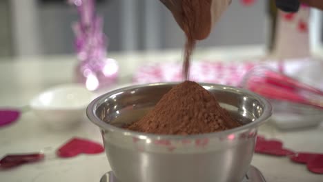 close up of cacao powder going into a bowl of flour making a special valentine's day cake vegan chocolate cake eggless plant based dairy free