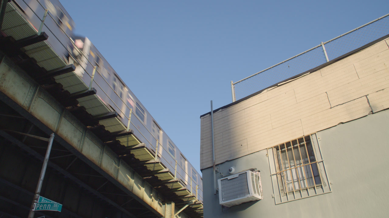 Establishing shot of the subway on elevated tracks in Brooklyn. Shot from a low angle in New York City.