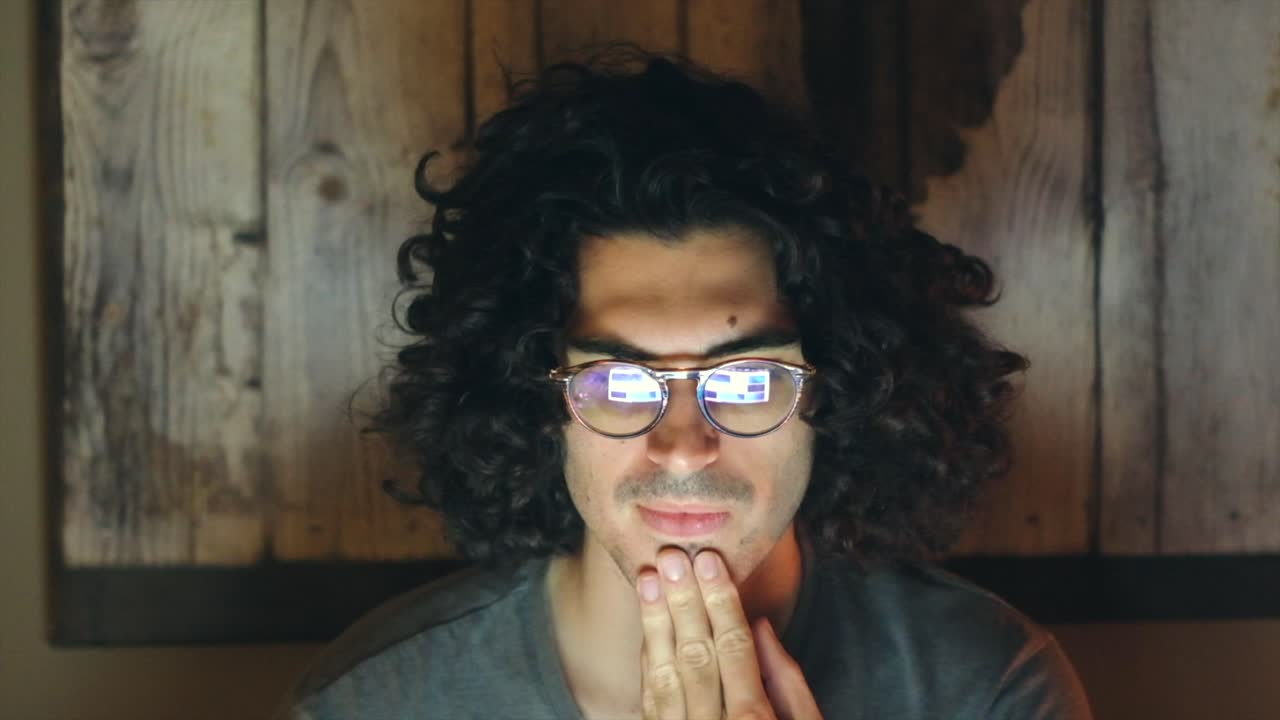 joven trabajando con una computadora portátil y revisando correos electrónicos en una habitación oscura