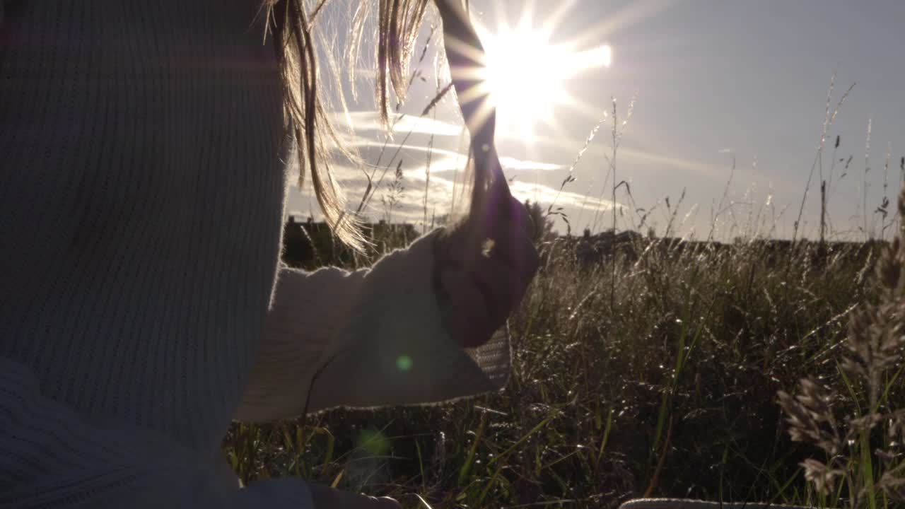 Woman playing with her long hair against sunshine background medium shot