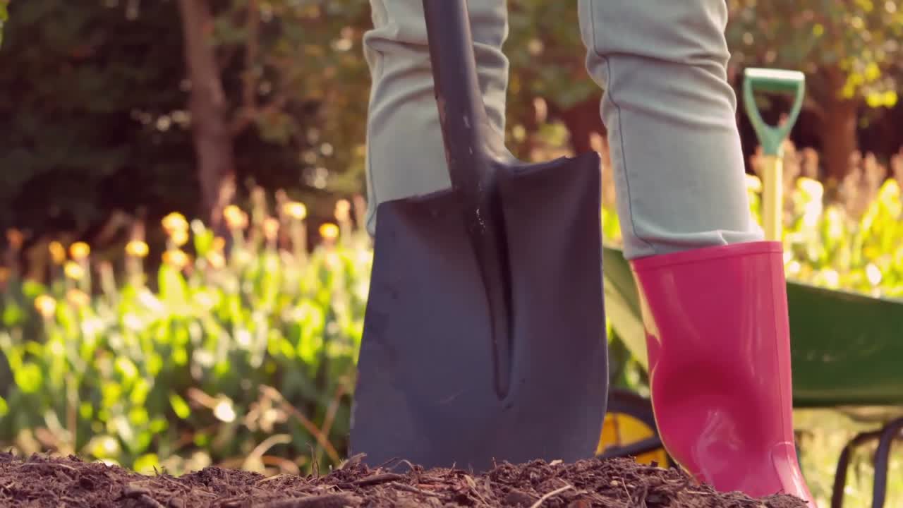 mujer con botas de goma rosadas usando una pala