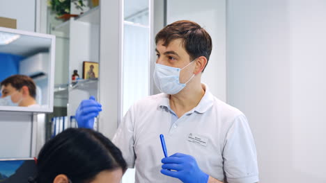 male teacher in mask and blue gloves speaking to his students. orthodontic course practice for future dentists.