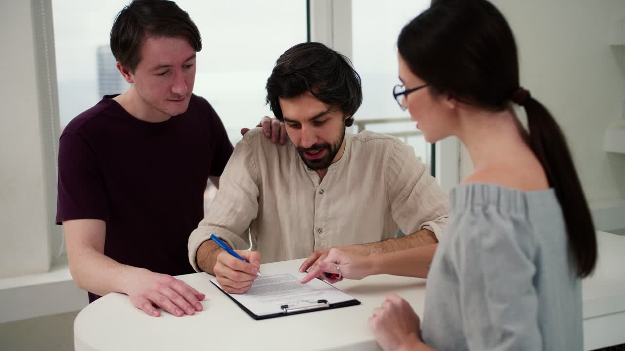 una pareja feliz firma un contrato para comprar una casa nueva con un agente inmobiliario en una cocina nueva