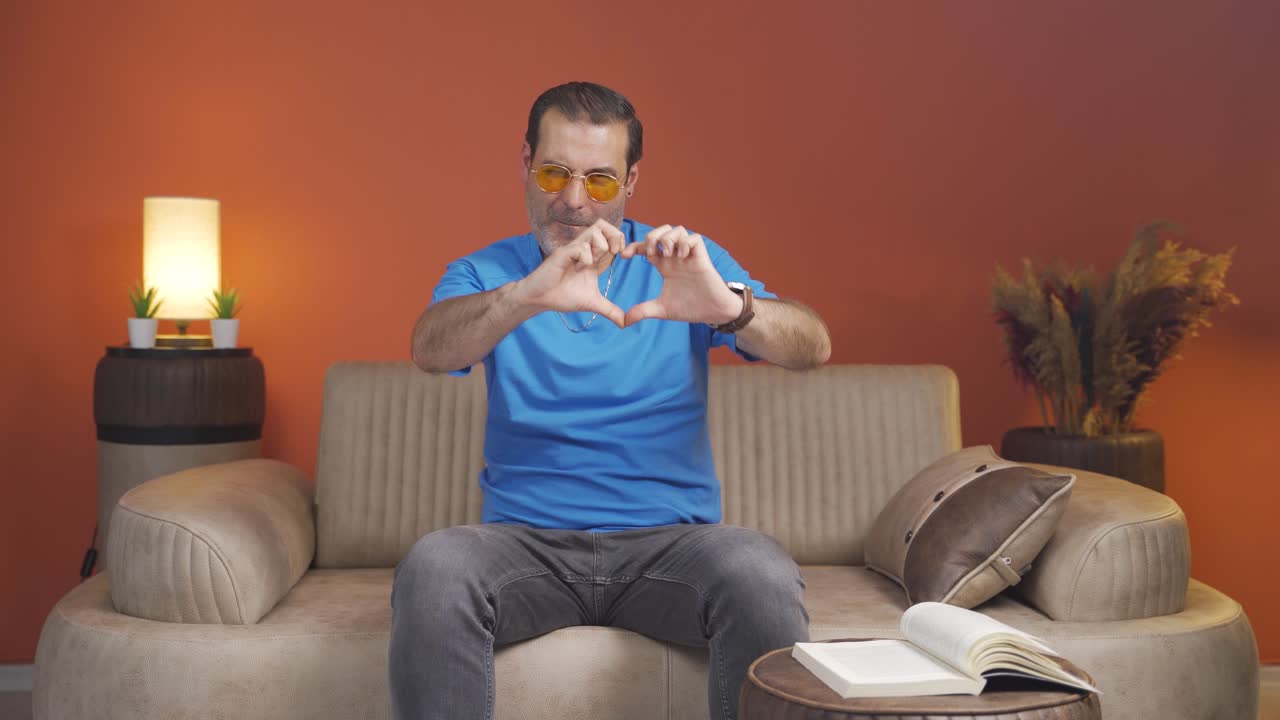 hombre haciendo una señal de corazón a la cámara.