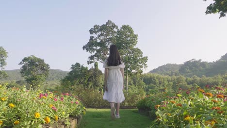 young  girl walking in a garden of flowers