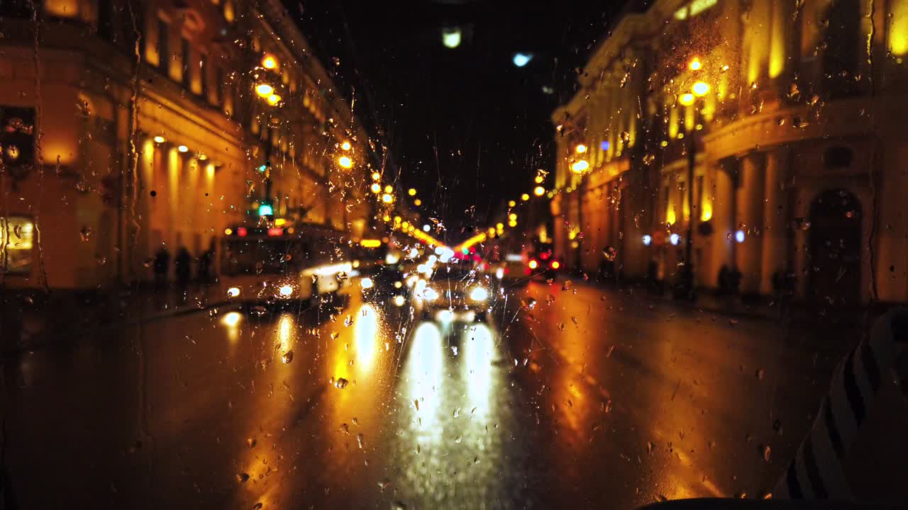 비가 내리는 동안 밤의 도시 거리에서 초점을 맞추지 않은 불빛