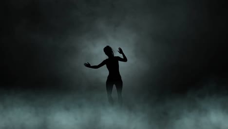 A-modern-youth-dance-performed-by-a-graceful-and-sexy-female-silhouette,-in-the-smoke-against-the-backdrop-of-spotlights