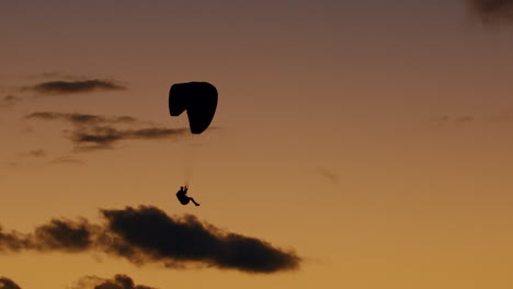 fotografía en cámara lenta con la silueta de un parapente volando sobre el océano atlántico de portugal, mientras disfruta de los colores del cielo