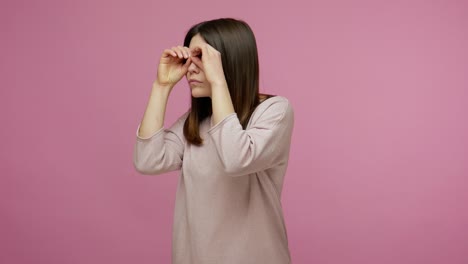 brunette woman looking around through binoculars fingers gesture, watching distance, viewing with attention