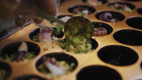 putting a scoop of mixed vegetables into takoyaki pan