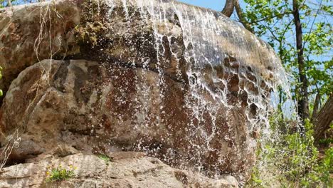 beautiful waterfall from a cliff in the forest. 4k video of flowing water, flowing stream among stones. stream in the forest