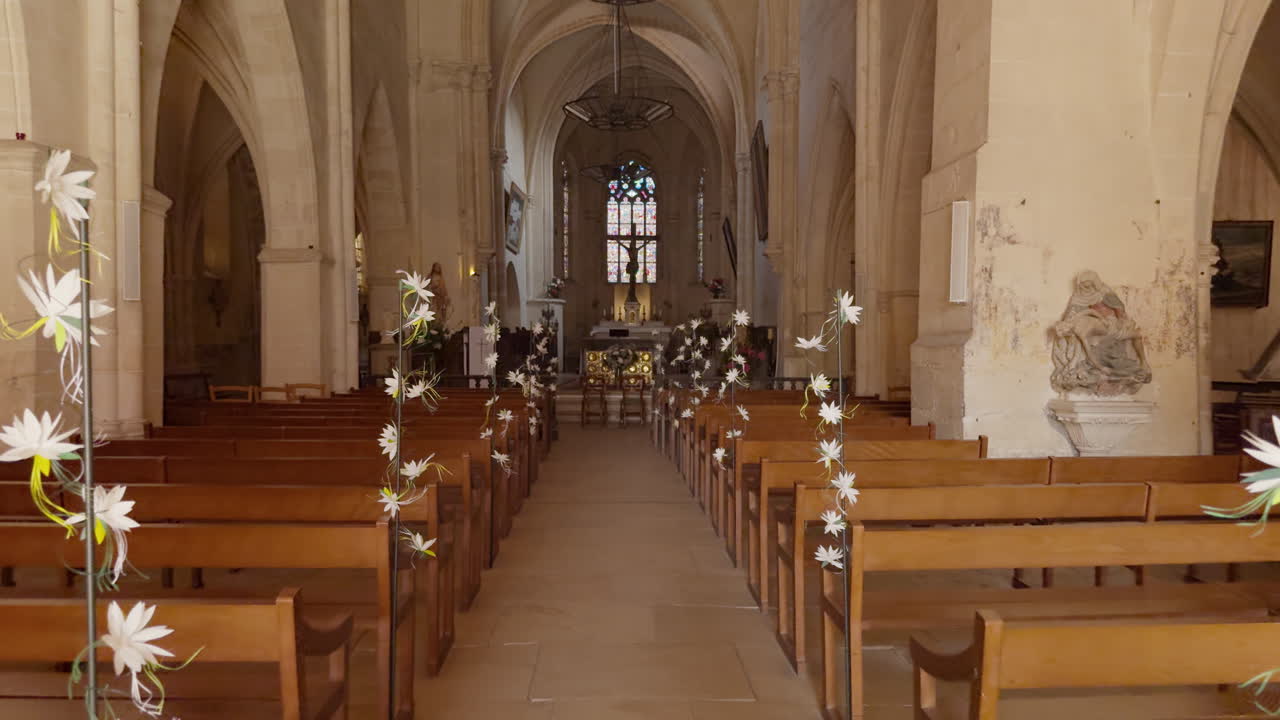 Interior POV shot of delicate floral garlands draped along the ends of pews in Saint-Fargeau Church of France