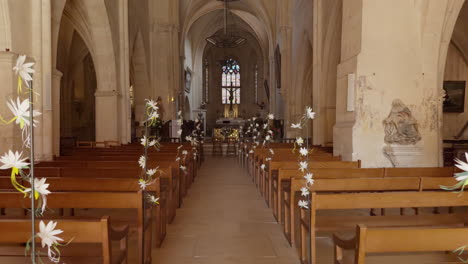 interior pov shot of delicate floral garlands draped along the ends of pews in saint-fargeau church of france