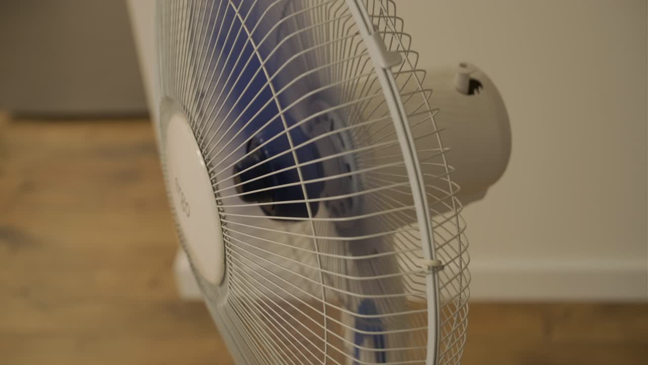 Close-up de um ventilador elétrico branco com pás azuis girando
