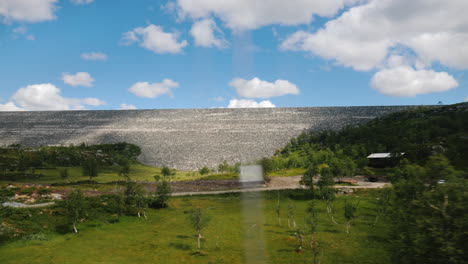 view from a car window at a landscape in norway with a large stone dam