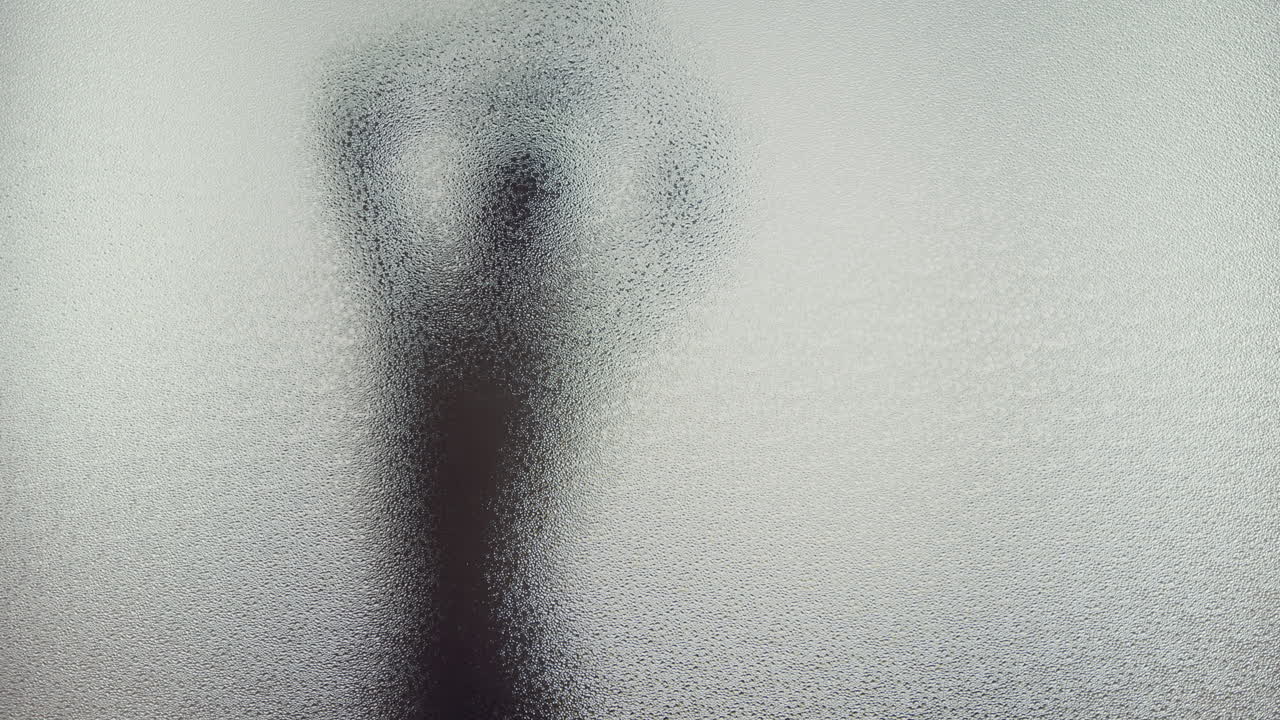A female silhouette behind the frosted window dances slowly