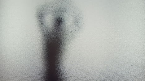 a female silhouette behind the frosted window dances slowly