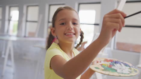 video de una niña caucásica sonriente pintando durante las clases de arte en la escuela