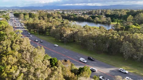 aerial footage captures vehicles moving along a tree-lined highway in gold coast, australia, under clear skies and natural lighting