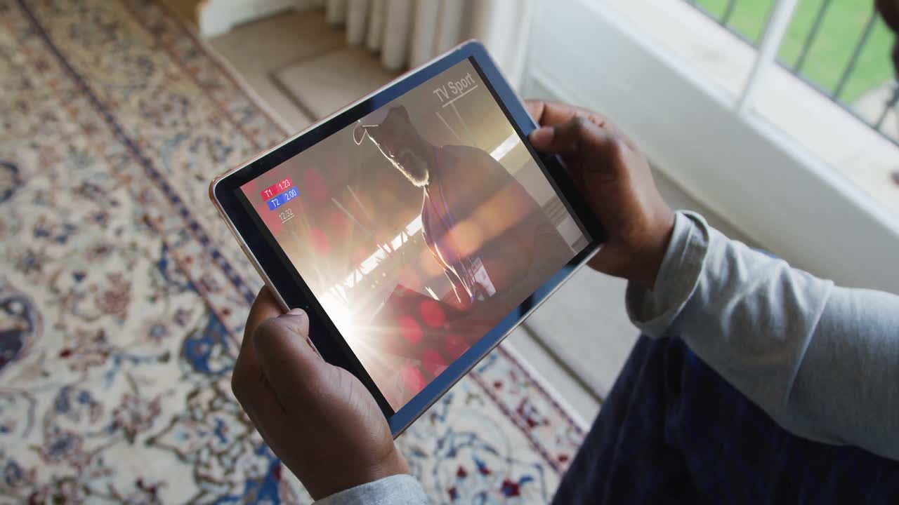 compuesto de un hombre sentado en casa, viendo un evento deportivo en la tableta