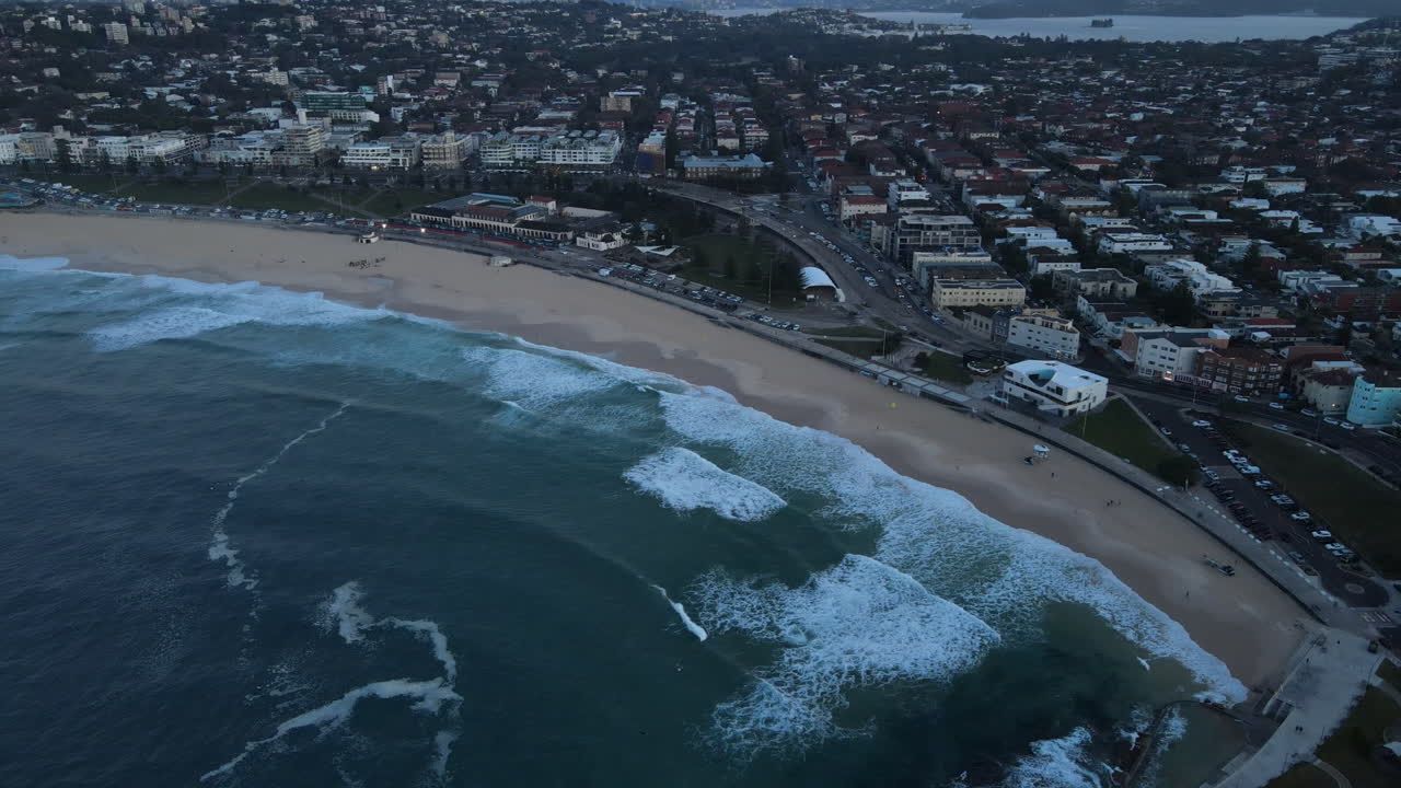 High Drone shot along Bondi beach with waves lapping and clear beach