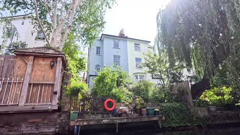 narrowboat passing by lush greenery and buildings