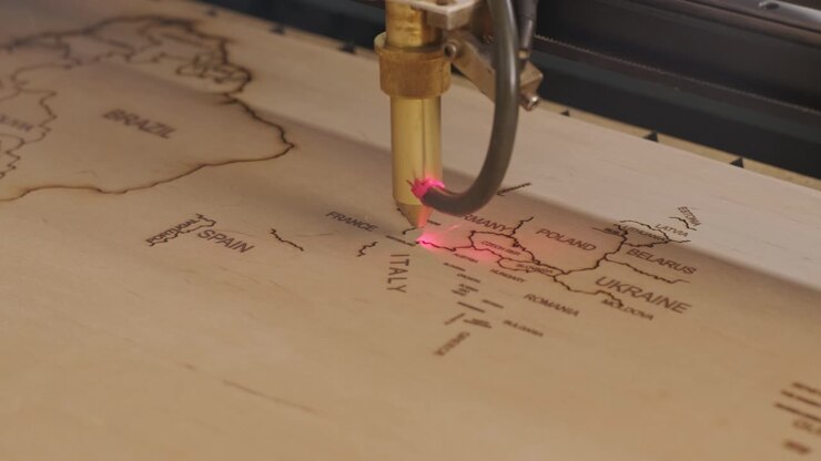 Macchina da taglio laser CNC taglia una mappa del mondo su tavola di legno e compensato