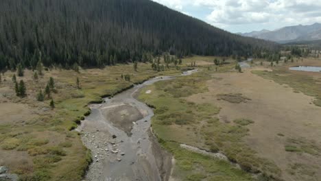 Aerial-over-river-with-mountains-in-background-in-Colorado