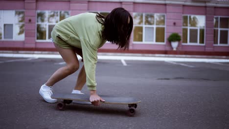 Das-Mädchen-Steigt-Vom-Skateboard,-Hebt-Es-Auf-Und-Bewegt-Sich-Weiter.-Jugendunterhaltung,-Fahrzeug,-Hobby