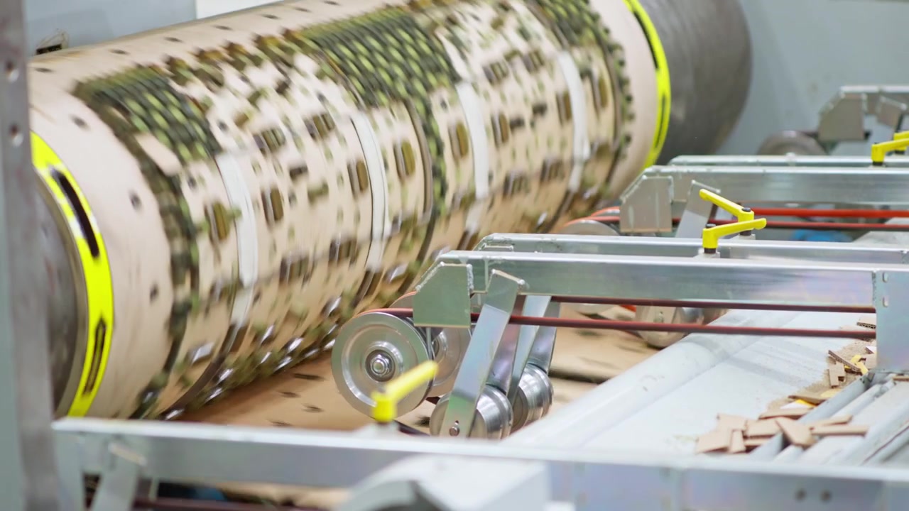 Roterende industriel trykcylinder behandler papmateriale på produktionslinje, udskærer dele for strukturel effektivitet.