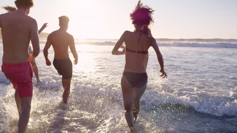 diverse group of friends swimming in the sea at sunset