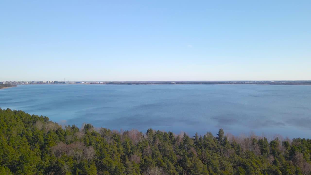 Gorgeous ascending aerial drone footage of Ülemiste lake in Tallinn Estonia that is a large water reservoir for the city during a beautoful sunny day. Surrounded by large green pine forest, city seen.