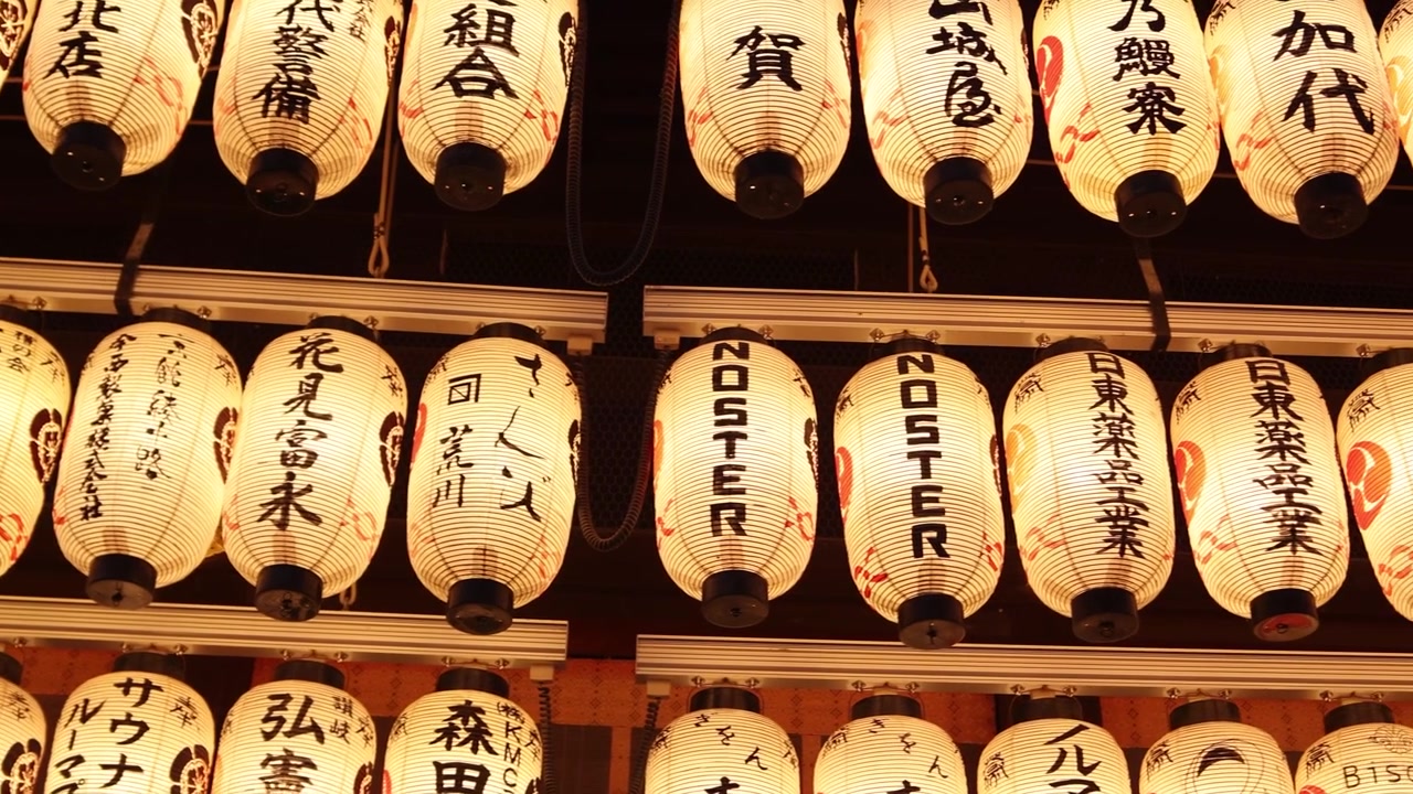 Vista ravvicinata di file di lanterne di carta illuminate al Santuario Yasaka, con iscrizioni giapponesi che brillano di luce calda durante la notte nello storico quartiere di Gion a Kyoto